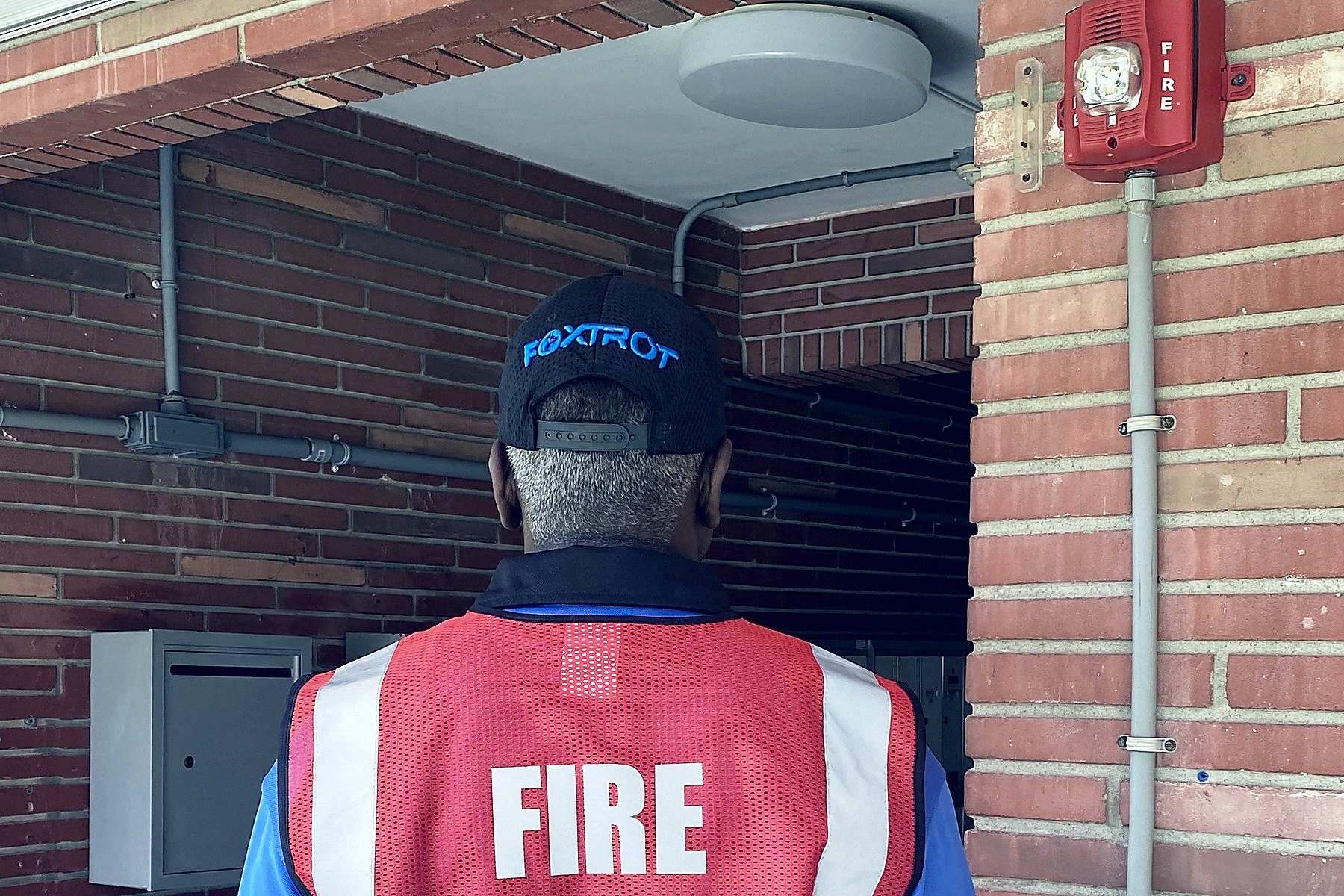 Foxtrot fire watch officer on rounds beneath a building fire alarm horn and strobe