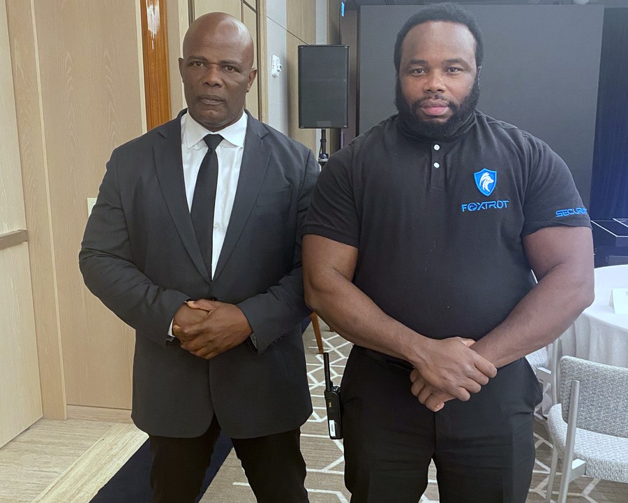 Two Foxtrot officers on an event post in a South Florida hotel ballroom — one suited, one in uniform
